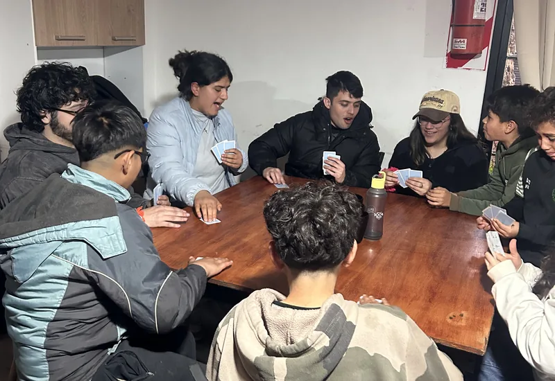 Jóvenes sentados alrededor de una mesa, compartiendo una tarde en el Hogar Sierra Dorada.
